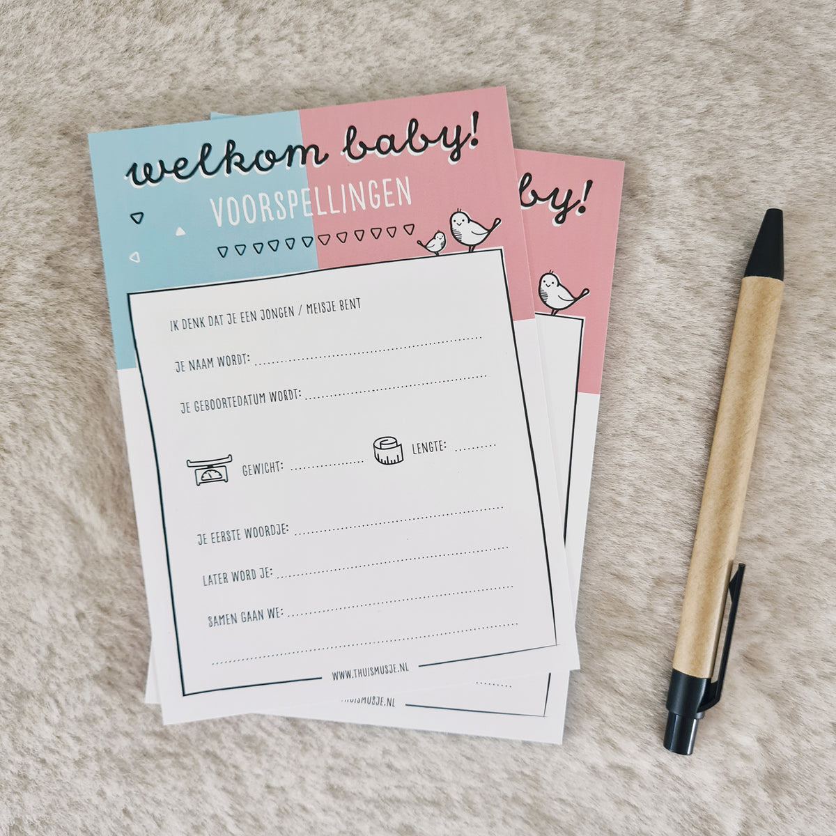 Sfeerfoto van stapeltje welkom baby voorspellingskaarten voor babyshower op A6 formaat met pen ter indicatie van grootte.