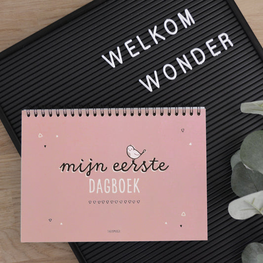 Sfeerbeeld mijn eerste dagboek roze, waarbij het gesloten boek op een letterbord ligt met de tekst Welkom wonder.