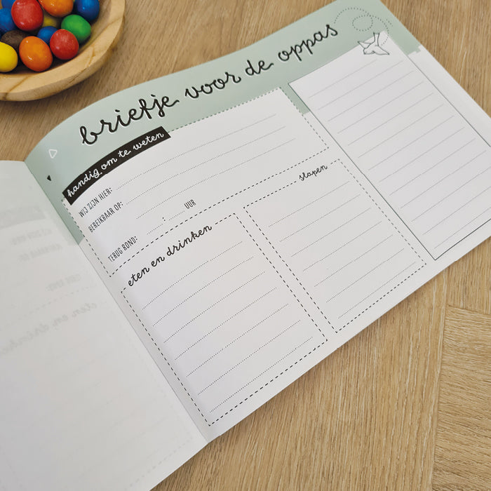 Voorbeeld van links gelijmd notitieblok met tekst briefje voor de oppas. Op tafel met een schaaltje m&m's.
