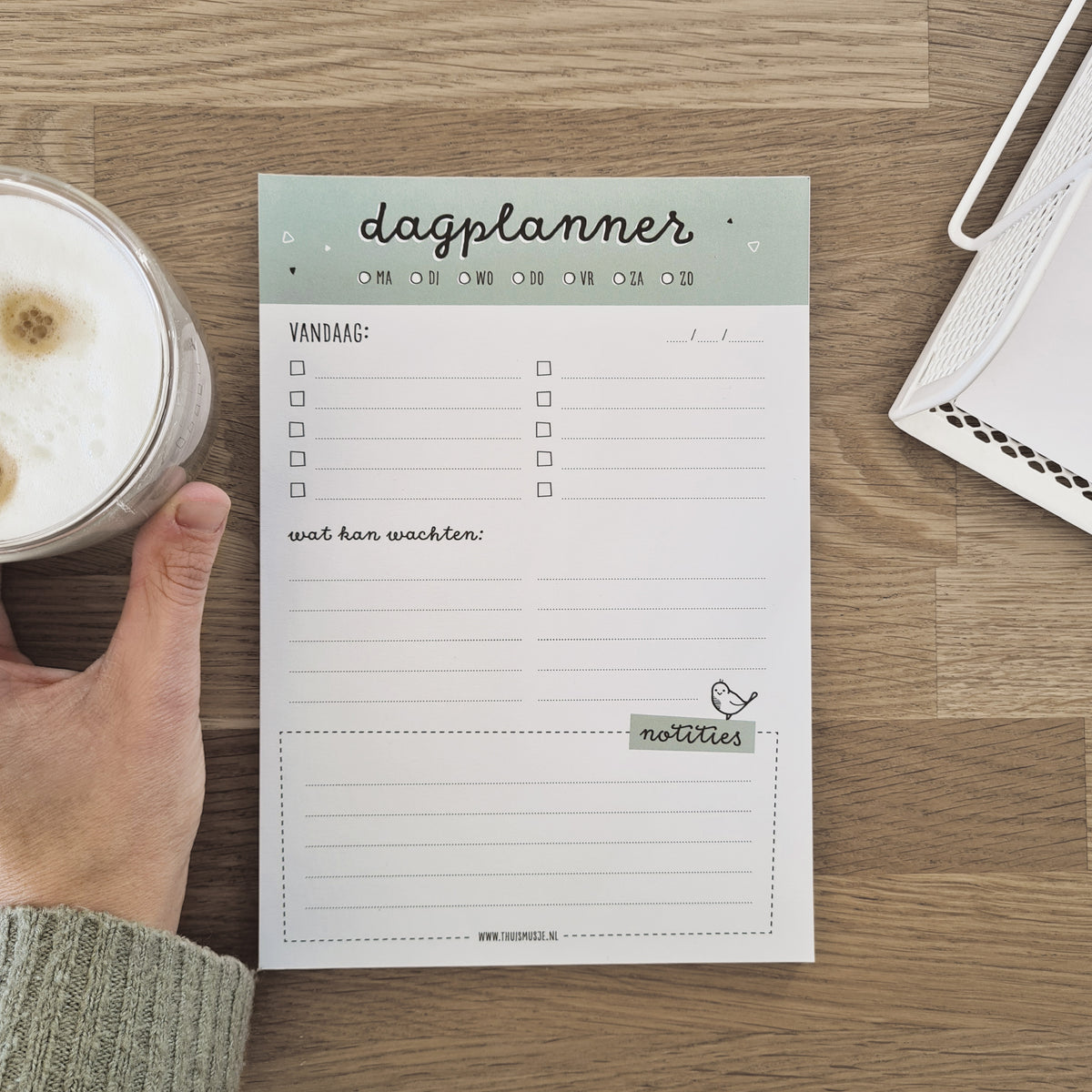 Sfeerbeeld van dagplanner op tafel met kop koffie in de hand. 