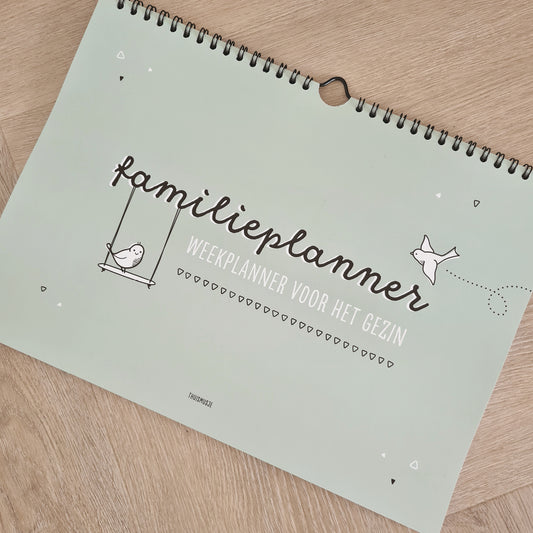 Sfeerfoto van familieplanner op houten tafel. Extra tekst welke op voorzijde staat is: weekplanner voor het gezin. 