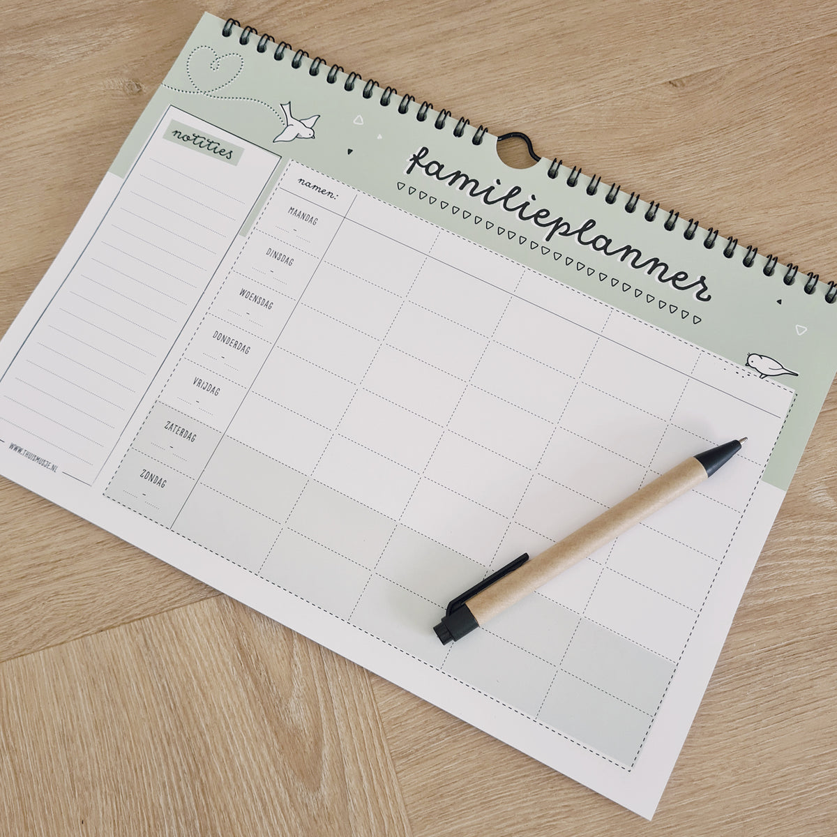 Sfeerfoto van binnenzijde planner met bovenop een pen. Ontwerp is zwart wit met licht groene details. 