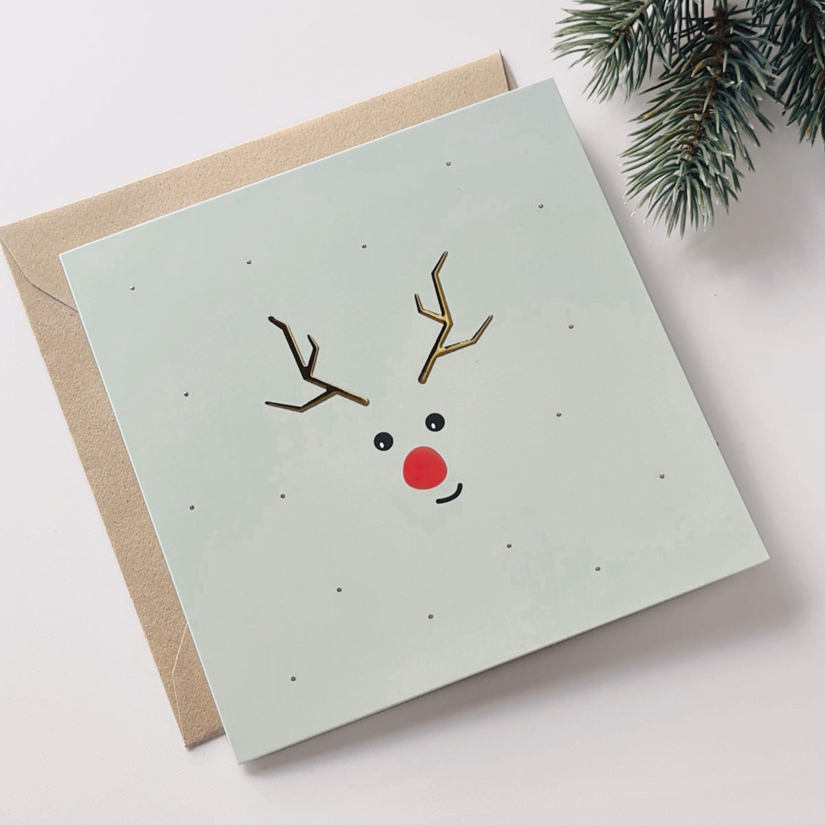 kerstkaart met lichtgroene achtergrond en eenvoudige bedrukking van rendier met goudfolie. Schattig en subtiel ontwerp.