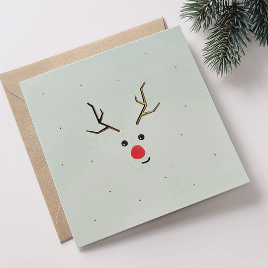 kerstkaart met lichtgroene achtergrond en eenvoudige bedrukking van rendier met goudfolie. Schattig en subtiel ontwerp.