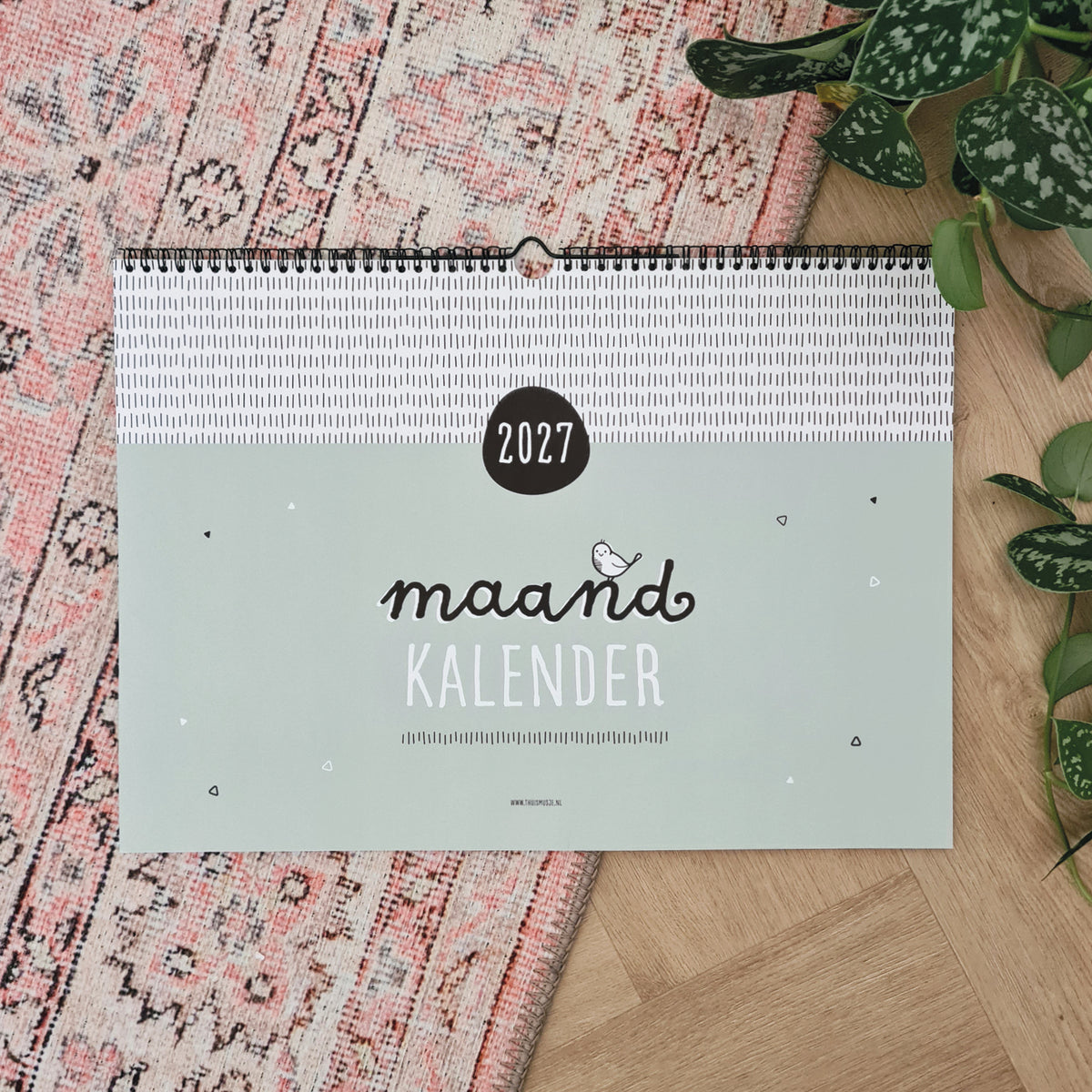Sfeerfoto voorzijde A3 maandkalender 2027, op roze Marrokaans kleed met plant ernaast. 