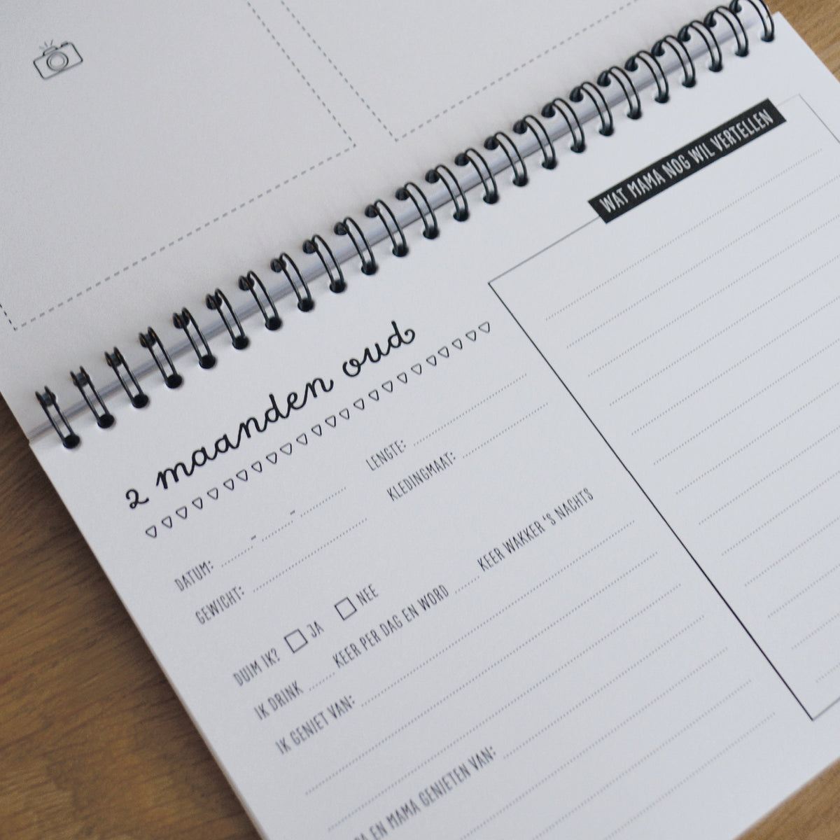 Sfeerbeeld van binnenzijde pagina met titel 2 maanden oud. Verschillende vragen om te beantwoorden en ruimte om foto's in te plakken. Sfeervol speels ontwerp in zwart wit. 