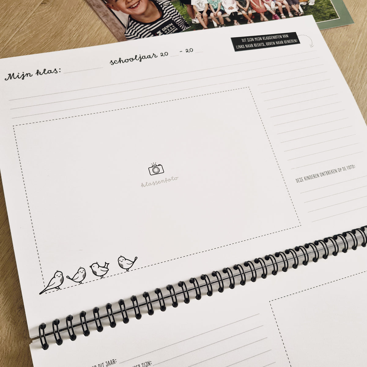 Close-up van binnenwerk schoolfotoboek. Te zien is ruimte voor een grote klassenfoto, schrijfruimte voor welke klas, schooljaar en klasgenoten. 