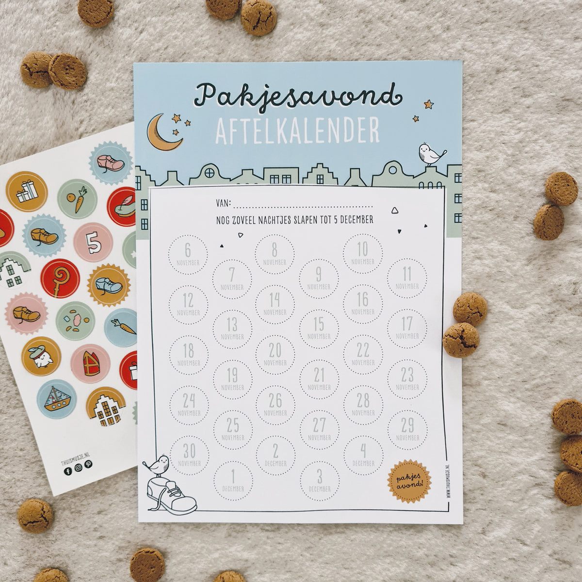 Sfeerfoto van pakjesavond aftelkalender met kleurrijk stickervel. Rondom is gestrooid met pepernoten. 