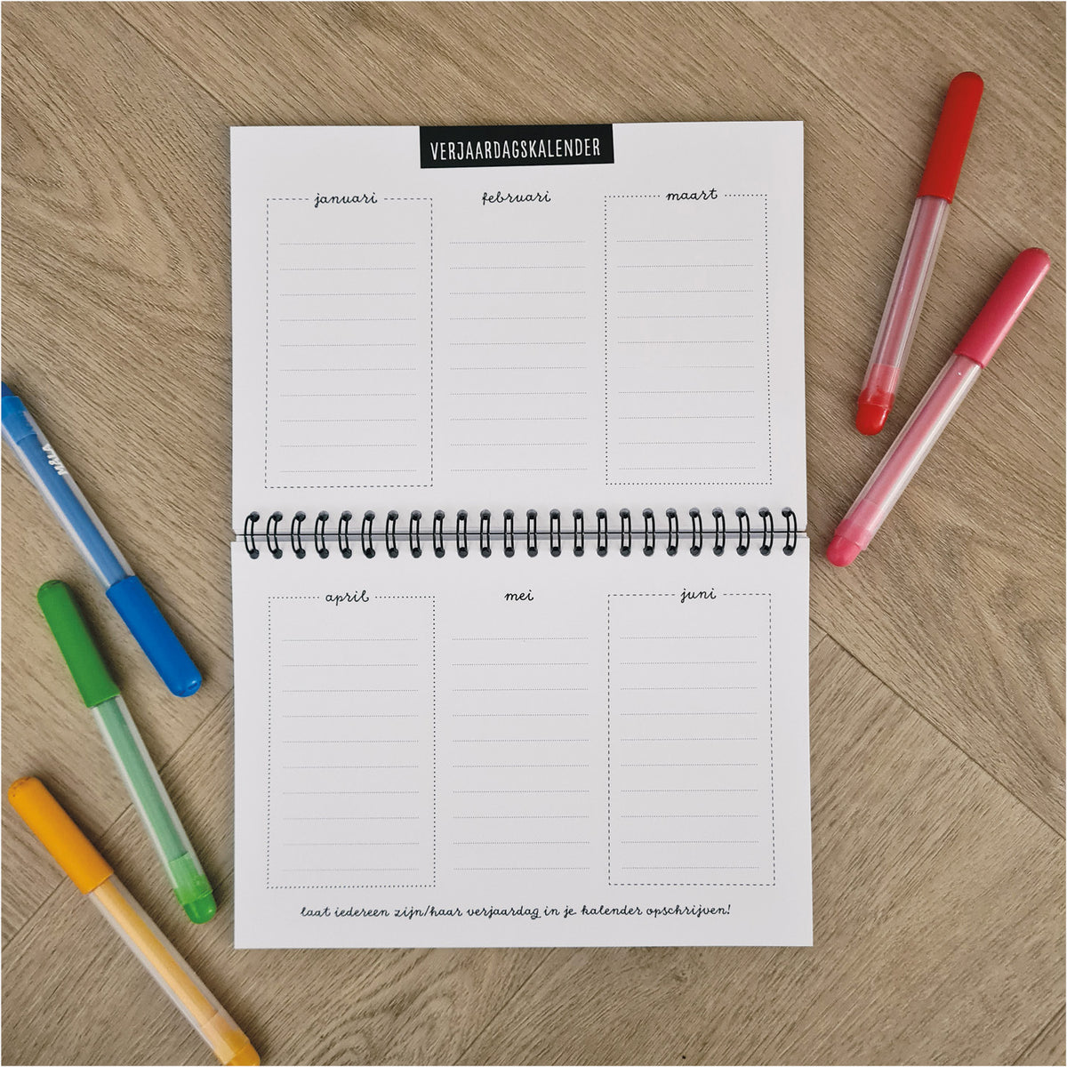 Sfeerfoto opengeslagen vriendenboekje op houten ondergrond met gekleurde stiften rondom. Opengeslagen op de verjaardagskalender in het midden van het boekje. 