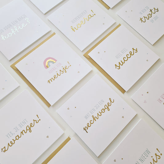 Foto van allerlei wenskaarten met goudfolie uit dezelfde collectie bij elkaar op tafel. Subtiel en warme ontwerpen met kraft envelop.