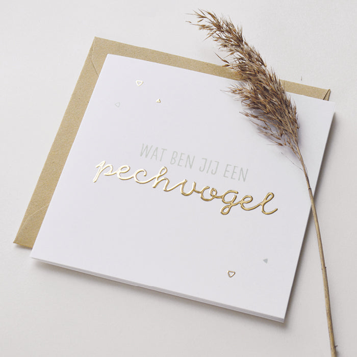 Wenskaart met goudfolie met de tekst wat ben jij een pechvogel. Weergegeven met kraft envelop
