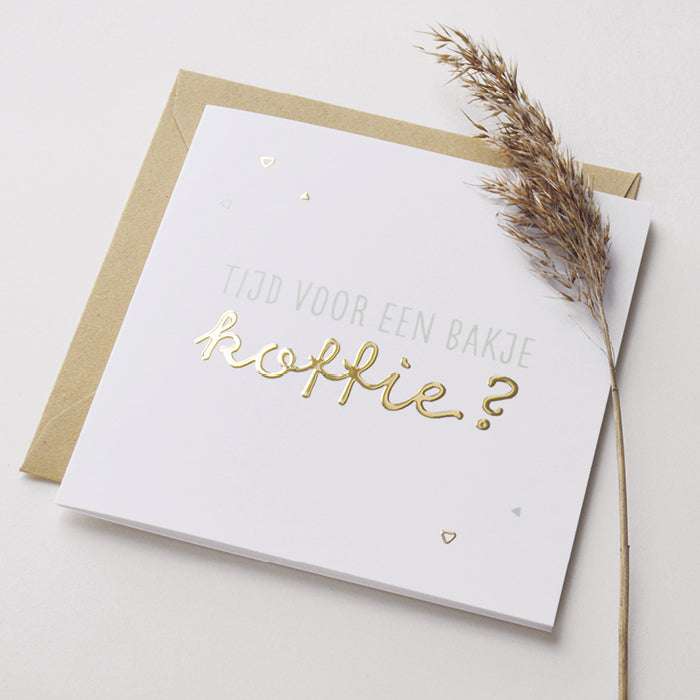 Wenskaart met goudfolie met de tekst tijd voor een bakje koffie? Weergegeven met kraft envelop